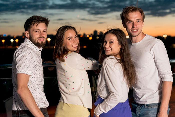 Four young adults smiling together outdoors at sunset, capturing a moment linked to childhood trauma and family tradition.