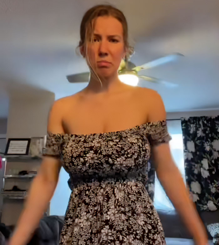 Woman with serious expression wearing floral dress after viral breast reduction, facing online trolling from men.