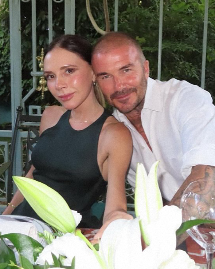 Victoria and David Beckham posing together at an outdoor dinner setting amid Brooklyn Beckham family drama.