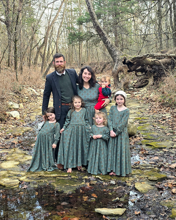 Family of six dressed similarly standing barefoot in a forest creek, reflecting off the grid living and poverty concept. Family of six dressed similarly standing barefoot in a forest creek, reflecting off the grid living and poverty concept.
