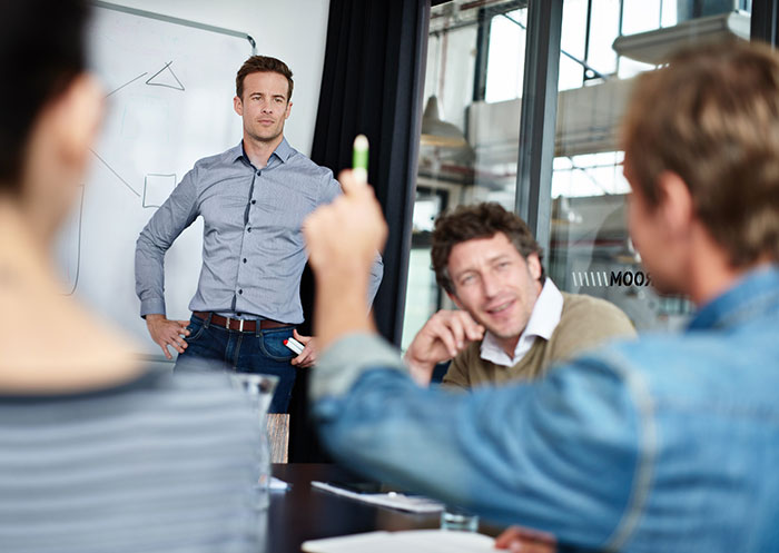 Man presenting a hilarious pitch during a restaurant meeting with business executives after a snarky letter discussion.