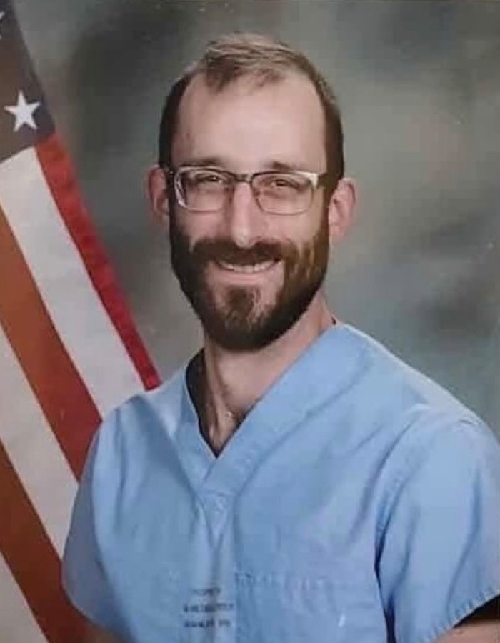 Alex Pretti in light blue scrubs smiling, with glasses and beard, featured in viral clips before fatal encounter debate. Alex Pretti in light blue scrubs smiling, with glasses and beard, featured in viral clips before fatal encounter debate.