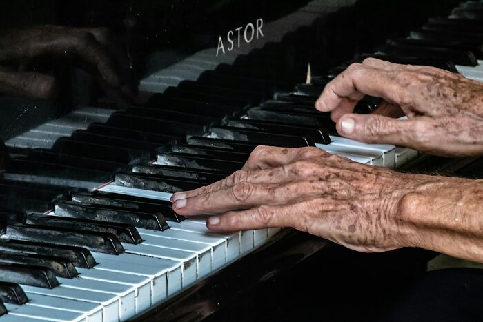 Elderly hands expertly playing piano keys, showcasing surprising intelligence and skill in music performance.