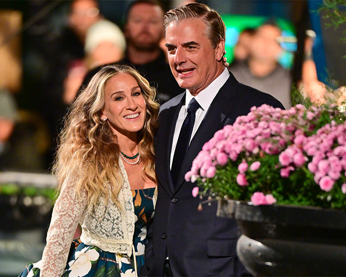 Chris Noth and Sarah Jessica Parker attending an event with flowers in the foreground and blurred crowd background. Chris Noth and Sarah Jessica Parker attending an event with flowers in the foreground and blurred crowd background.