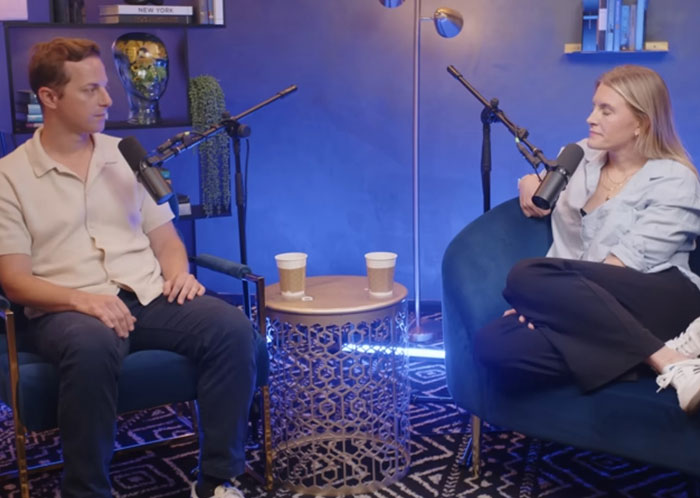 Two people seated in a podcast studio with microphones discussing celebrity infidelity scandals in a casual interview setting.