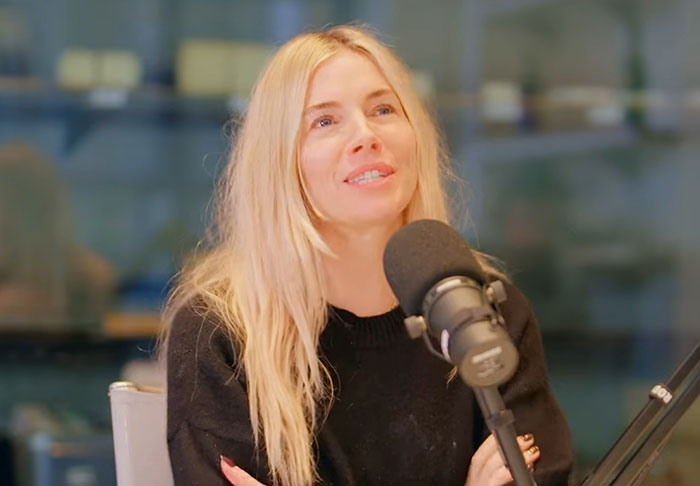 Blonde woman speaking into a microphone during a podcast recording about celebrity infidelity scandals.
