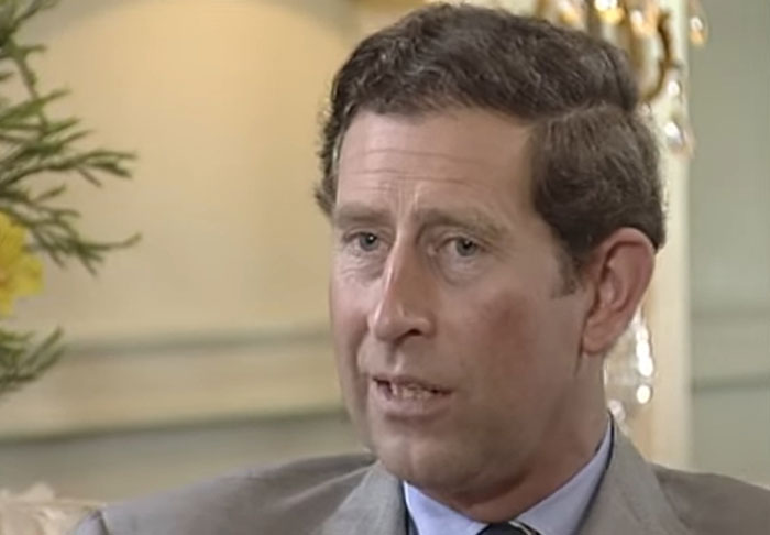 A man in a gray suit speaking during an interview about celebrity infidelity scandals in a formal indoor setting.