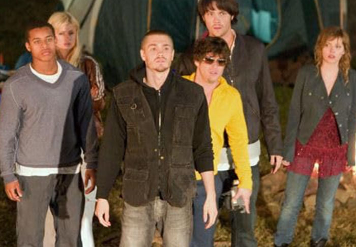 Group of young adults outdoors at night, representing the worst celebrity infidelity scandals with tense expressions and casual attire.