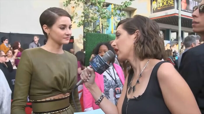 Celebrity answering an interviewer’s invasive question during a red carpet event with crowd in the background