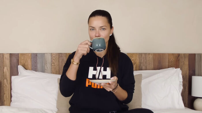 Woman in casual clothes sitting on a bed drinking coffee, illustrating savage responses celebs give to invasive questions.