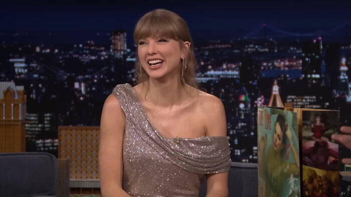 Taylor Swift on a late-night talk show set, smiling and sharing savage responses to annoying interview questions.