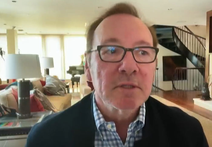 Middle-aged man wearing glasses and a checkered shirt, speaking in a well-lit living room about celebrities out of touch with reality.