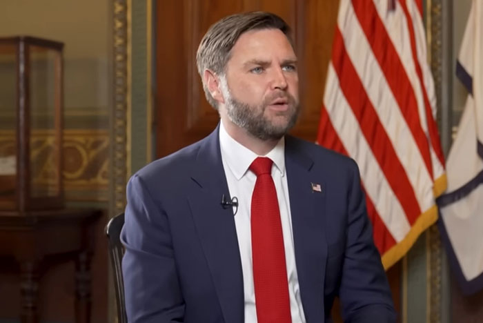 Man in suit and red tie speaking in an interview setting, illustrating celebrities out of touch with reality moments.