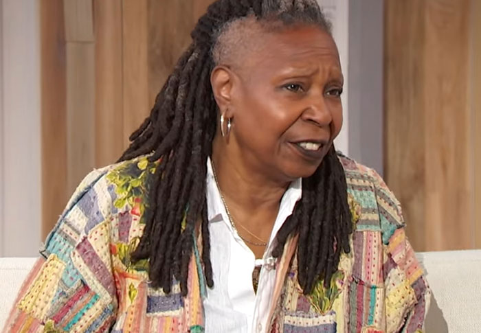 Celebrity with dreadlocks wearing a colorful patchwork jacket, appearing surprised and out of touch with reality in an interview setting.