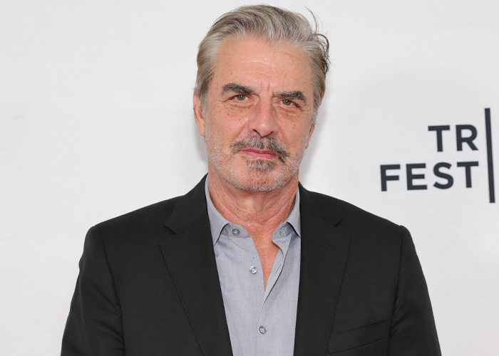 Chris Noth at a TR FEST event, wearing a black blazer and gray shirt, discussing his friendship with Sarah Jessica Parker.