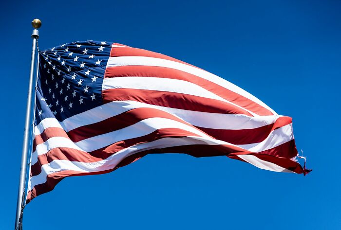 American flag waving against clear blue sky, illustrating things normal in their country but offensive elsewhere.