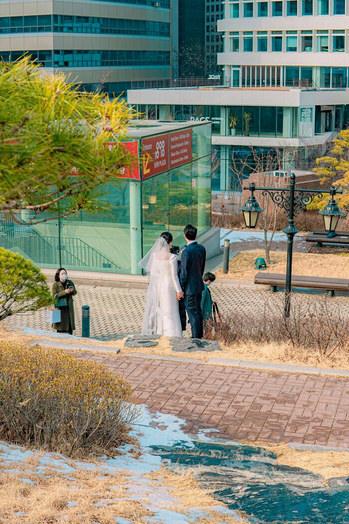 Bridal couple in wedding attire walking near urban park, highlighting moments former cult members recognize cult experiences.