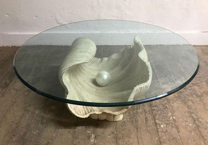 Mesa de centro con base escultórica en forma de concha y superficie de vidrio, idea de diseño interior moderno.