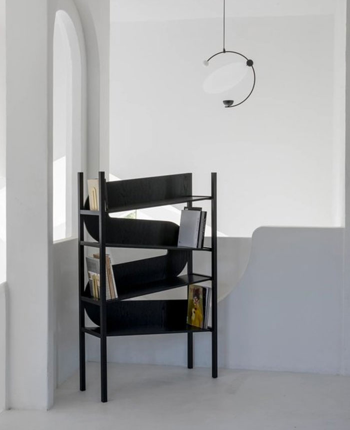 Modern black bookshelf with unique curved shelves in a minimalist room showcasing cool interior design ideas.