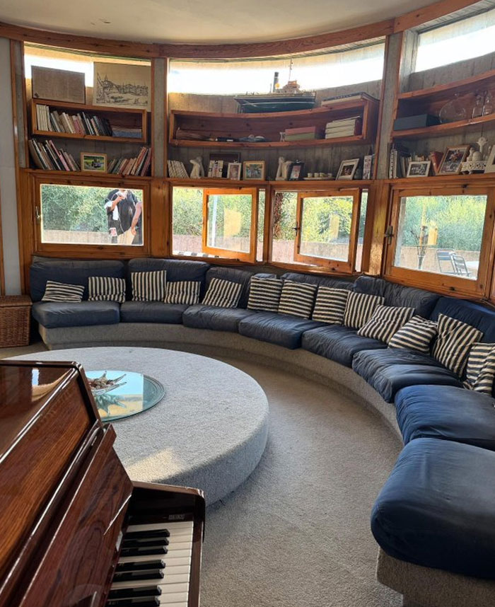 Sala de estar con sofá curvo, cojines a rayas y estanterías de madera, ejemplo de ideas de diseño interior fresco.