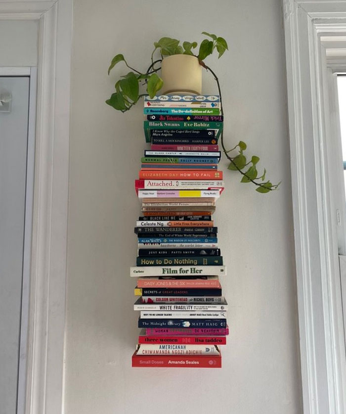 Stacked books mounted on a wall with a plant on top showcasing cool interior design ideas for unique home decor.