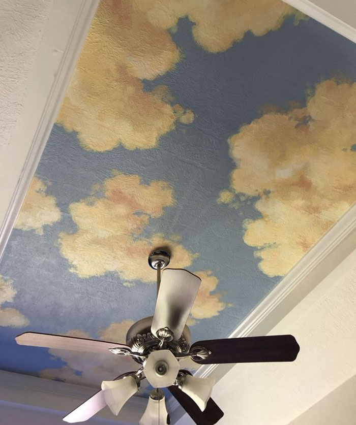 Ventilador de techo con pintura de nubes en el techo, una idea fresca de diseño interior para inspirar la renovación del hogar.