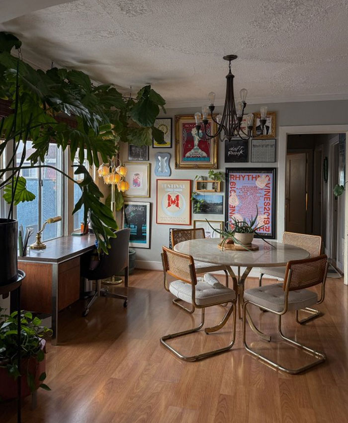 Cozy dining area with vintage chairs, round table, wall art gallery, indoor plants, and warm wood flooring interior design ideas.