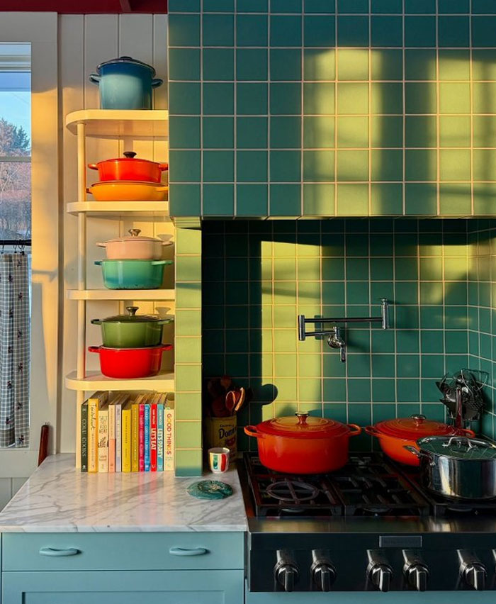 Cocina con azulejos verdes y cacerolas de colores brillantes como ideas de diseño interior moderno.