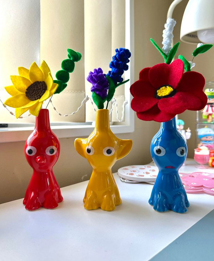 Colorful quirky vases with bright felt flowers displayed on a white surface, showcasing cool interior design ideas.