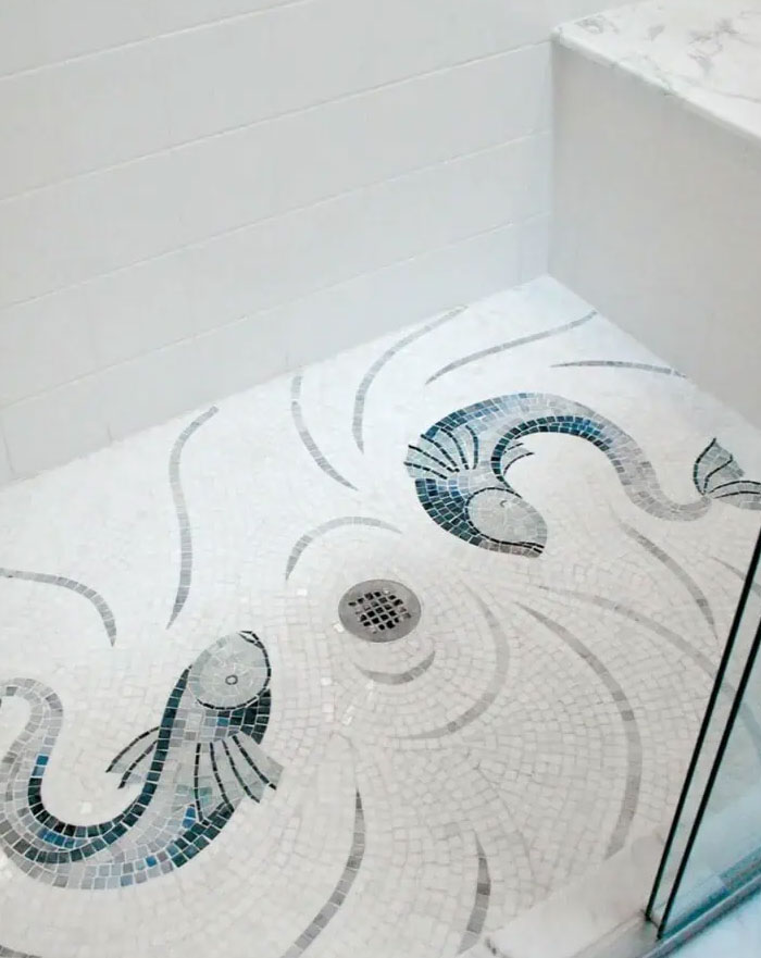 Suelo de ducha con diseño de mosaico de peces, una idea creativa de interiorismo para renovar tu hogar.