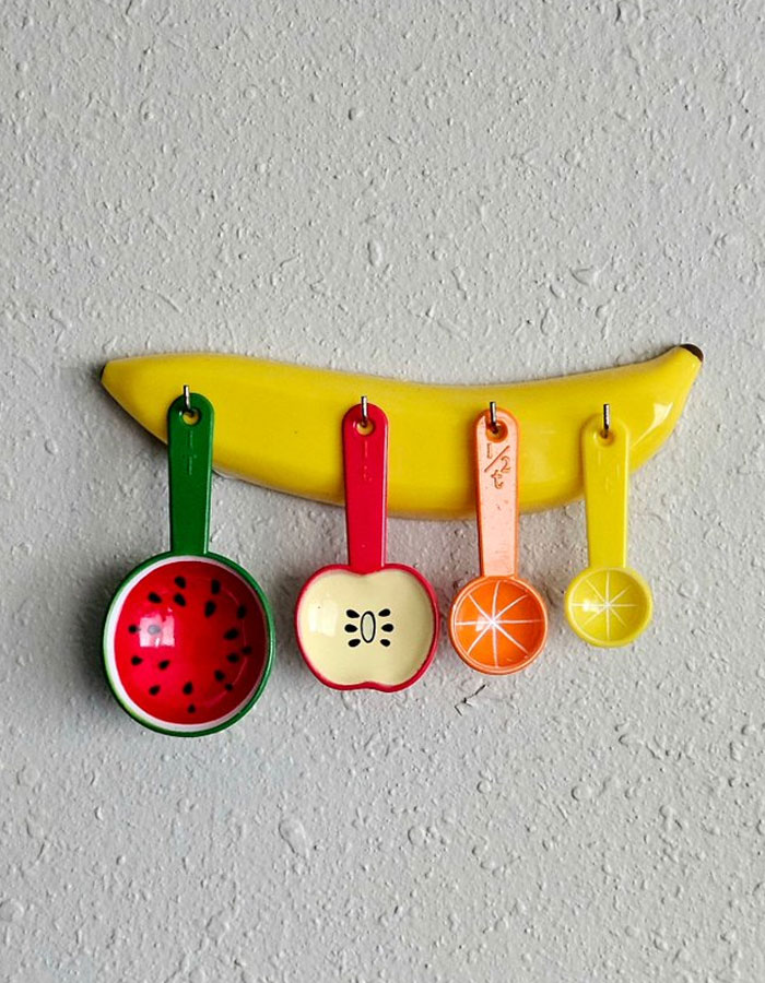 Colgador de pared con diseño de plátano y cucharas medidoras coloridas con motivos de frutas decoración interior original.