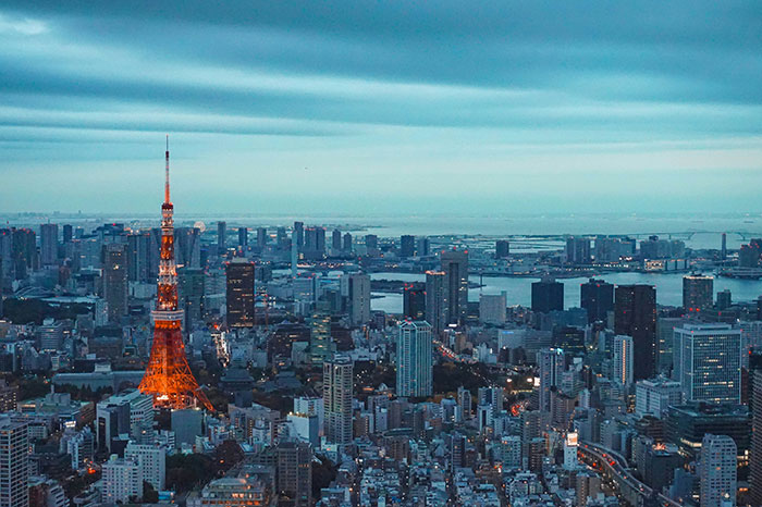 Tokyo skyline at dusk with illuminated Tokyo Tower and sprawling cityscape under a layered blue sky.