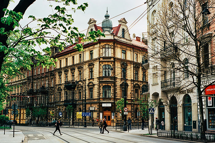 Historic city street with ornate corner building, pedestrians and tram tracks, representing coolest cities.