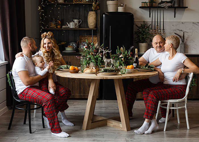 Two couples in matching plaid pants sharing a cozy moment around a decorated table, highlighting dumb house rules.