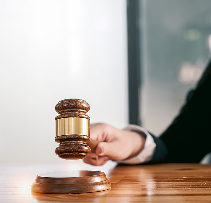 Judge striking wooden gavel on desk in courtroom, symbolizing a legal challenge or emergency call in a high-stakes case.