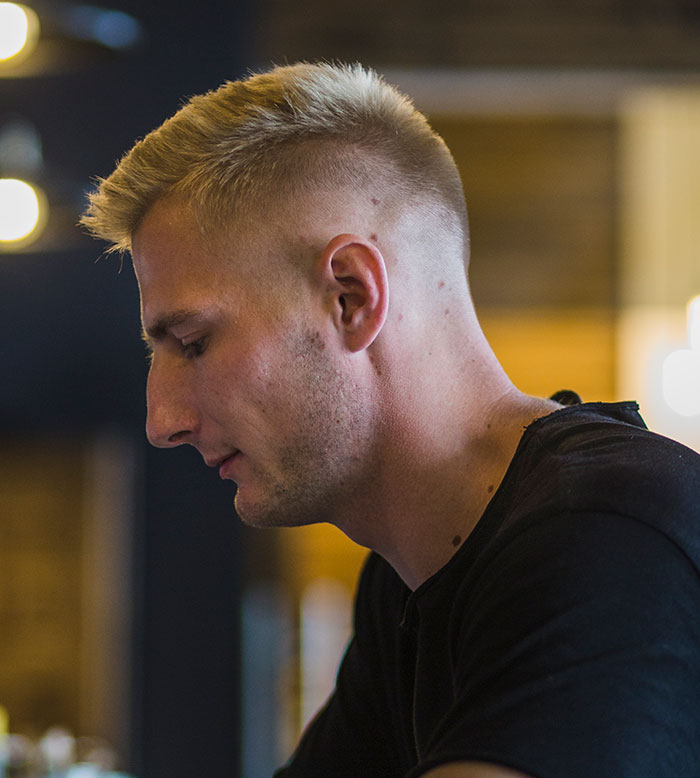 Young man with sharp intelligence lost in thought in a dimly lit indoor setting symbolizing mental sharpness