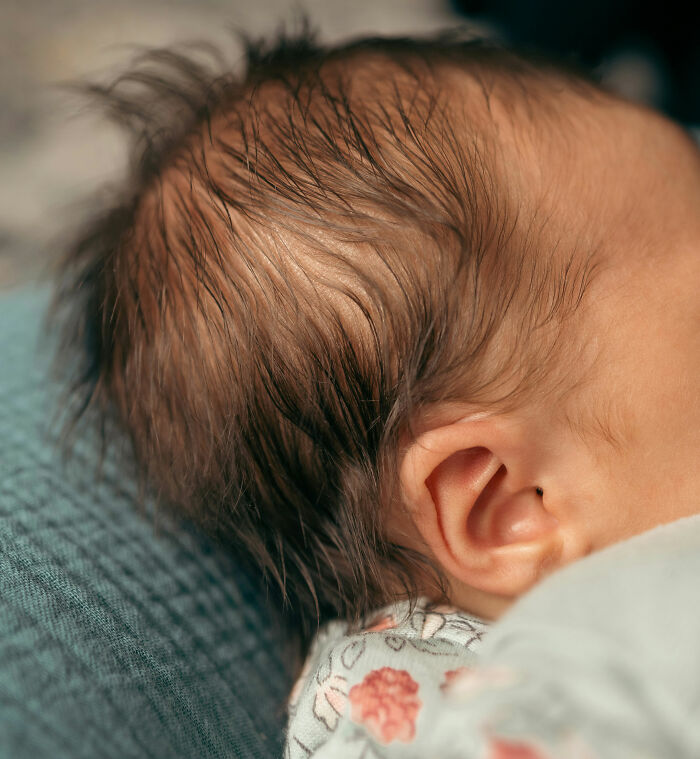 Close-up of a newborn baby’s head and ear, highlighting detailed features related to the human body facts.