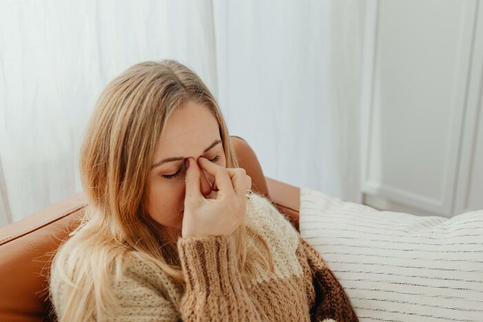 Woman in a cozy sweater rubbing her eyes, illustrating a creepy fact about the human body and discomfort.