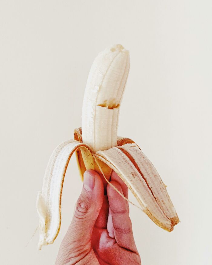 Hand holding a partially peeled banana symbolizing creepy facts about the human body and its unusual aspects.