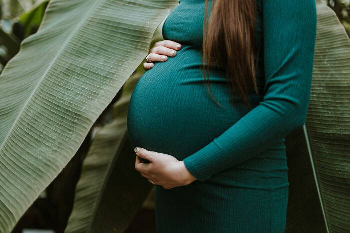 Pregnant woman in a green dress gently holding her belly, illustrating intriguing creepy facts about the human body.