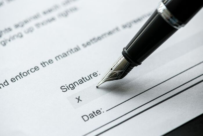 Close-up of a pen poised over a signature line on a document, highlighting awkward moments in the service industry.