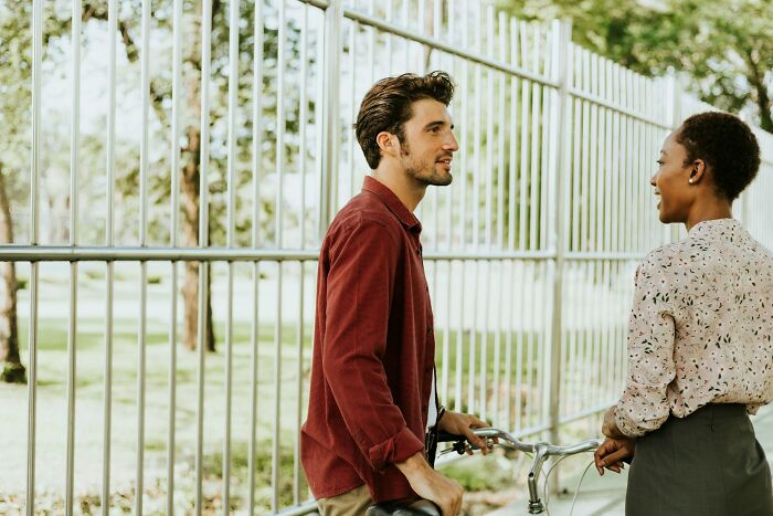 Two people talking outdoors near a fence, illustrating DNA test plot twist stories and surprising results.