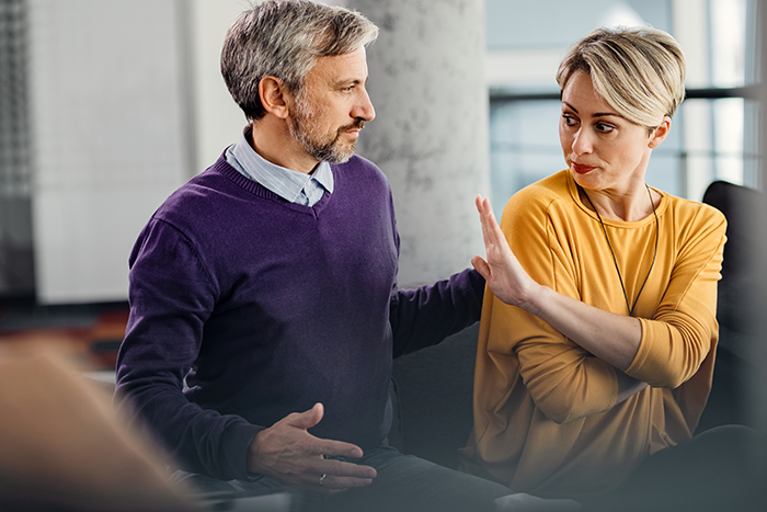 Middle-aged man and woman having tense conversation indoors, illustrating dad&rsquo;s mistress texts and family conflict on NYE.