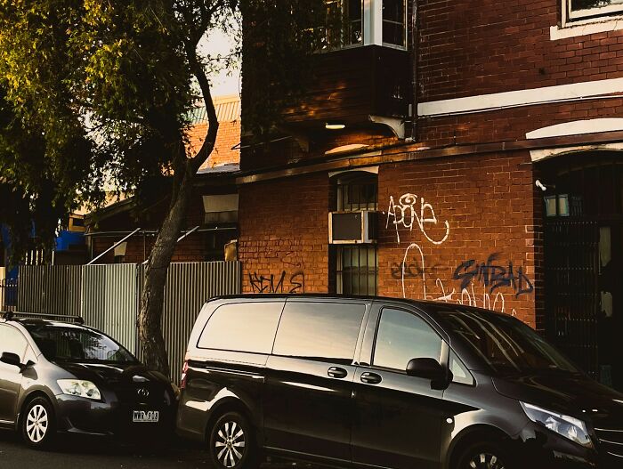 Black van parked in front of a brick building with graffiti, illustrating safety measures women take while living alone.