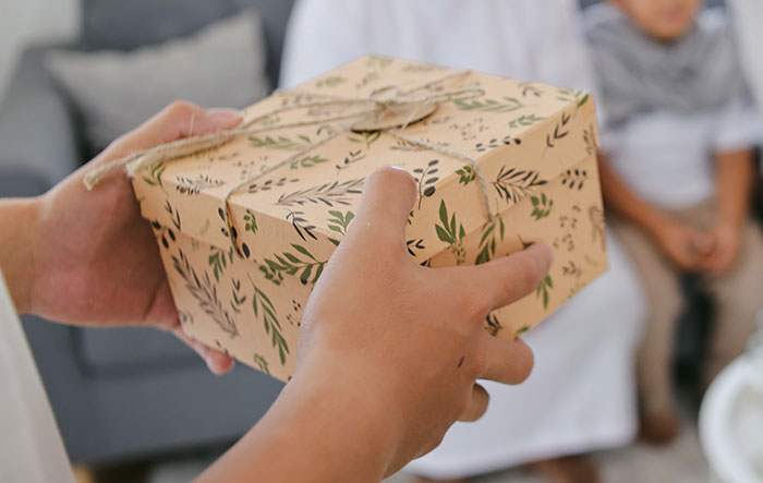 Hands holding a gift wrapped in floral paper, symbolizing a dangerous gift from mom in a family setting.