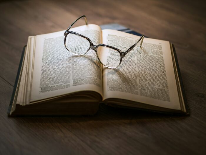 Open book with reading glasses resting on top, representing cultural insights from people sharing things normal in their country but offensive elsewhere.