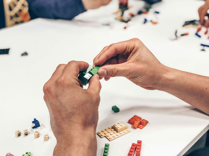 Hands assembling tiny cottages with building blocks, illustrating a mom's resentment toward cheerleader ambitions. Hands assembling tiny cottages with building blocks, illustrating a mom's resentment toward cheerleader ambitions.