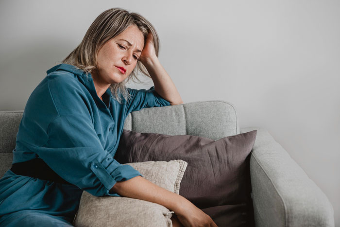 Woman sitting on couch looking distressed, reflecting mom's resentment over daughter not being a cheerleader. Woman sitting on couch looking distressed, reflecting mom's resentment over daughter not being a cheerleader.