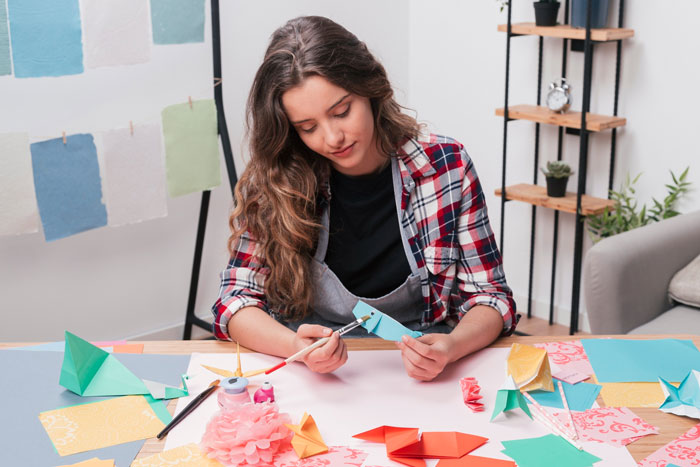 Young woman crafting tiny cottages from colorful paper, reflecting creative hobbies over cheerleading ambitions. Young woman crafting tiny cottages from colorful paper, reflecting creative hobbies over cheerleading ambitions.