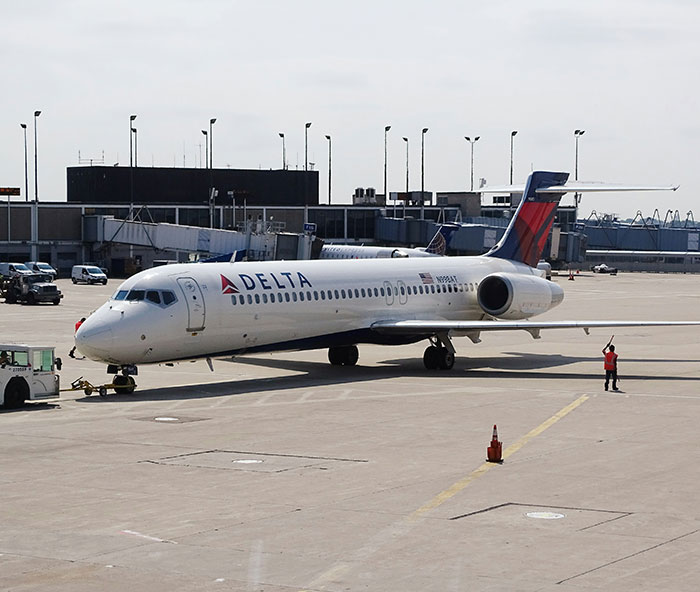 Delta airplane parked on the tarmac at the airport during a transatlantic flight operation with ground crew nearby.